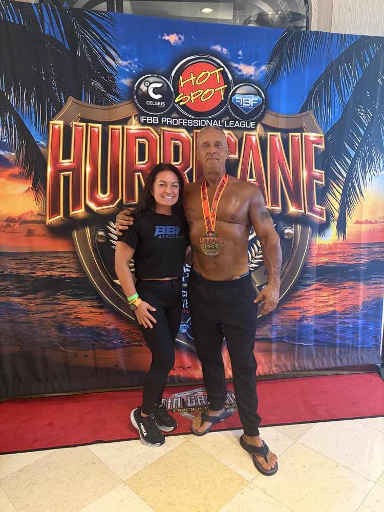 Coach Nick Meshew with his Hurricane Bay medal and Debbie in the black BBN Athletics crop tee